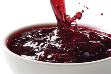 Red berry sauce pouring into a white bowl