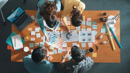 Top view of business team write graphic logo on meeting table with colorful sticky notes and design while explain idea. Project manager sharing idea and explain concept art to smart team. Symposium.