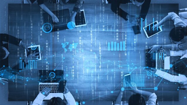 A business team utilizes digital technology in an office setting, collaborating on data analysis enhanced by visual graphs and interactive tablets for effective strategy development. Xenic - Powered by Adobe