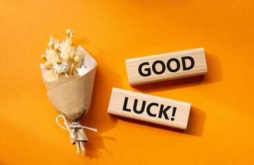 Good luck symbol. Wooden blocks with words Good luck. Beautiful orange background with bouquet of flowers. Business and Good luck concept. Copy space.