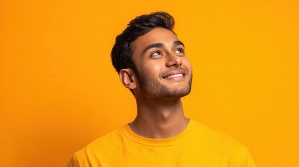 Obraz premium happy joyful smiling young indian man looking aside up thinking of new good opportunities dreaming feeling inspired and proud standing isolated on yellow background portrait no logos no brands ar 169