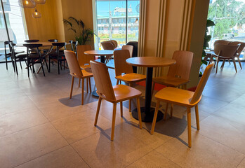 Wooden chairs and round table in a cafe. Minimalism, modern lifestyle, and urban dining atmosphere.