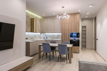 Modern kitchen-living room with light wood floors, gray cabinets, dining table with four chairs, and a unique bubble chandelier