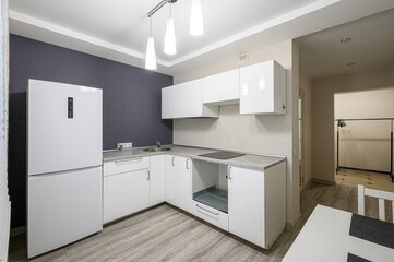 modern kitchen featuring white cabinets, a grey countertop, stainless steel sink, and wood floors. The decor is clean and simple, with pendant lighting above