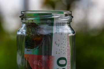 Swiss franc CHF banknote saving money in glass jar. Consumption and economy