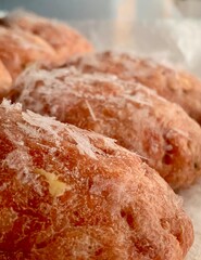 Delicious sweet pastries sit on a counter, their golden-brown crust dusted with sugar. Ideal for a delightful breakfast or a satisfying dessert