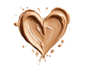 A heart-shaped, light beige cosmetic product, like foundation or concealer, is artistically swirled and textured, surrounded by small, splatter-like drops against a black background
