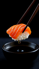Salmon nigiri held by chopsticks above soy sauce, dark background