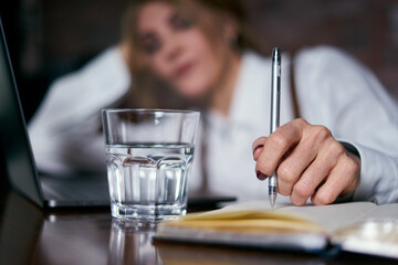 Beautiful senior woman working in cafe with laptop and writing in notepad
