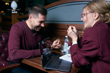 Happy business people working together on laptop in a restaurant
