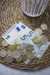 Euro banknotes and coins on a woven mat.