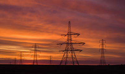 Electricity Pylons at Sunrise with Beautiful Colored Sky in the Background
