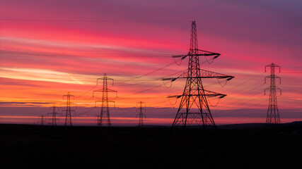 Electric Pylons at Sunrise Over Scenic Countryside Landscape