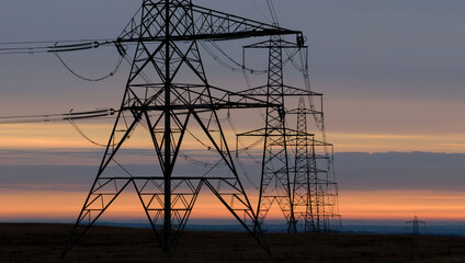 Power Transmission Towers at Sunrise Over Rural Landscape