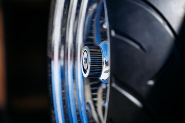 Close-up of a shiny chrome car wheel and tire with reflective surface details