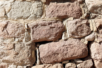Close-up of rustic brown stone block wall with mortar seams. High-resolution masonry background for architecture, patterns, restoration, archaeology, construction themes and design mockups.