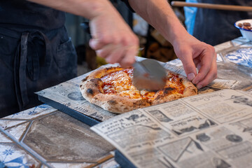 Fresh homemade pizza being sliced with a spatula on a rustic wooden table, showcasing crispy crust, aromatic toppings, and a cozy restaurant atmosphere for food lovers