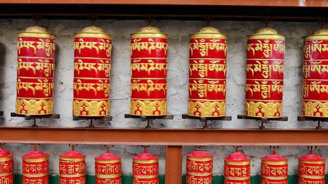 Rotating brass prayer wheels in Nepal monastery. Buddhist symbols, mantra engraving, spinning motion, cultural heritage, traditional ritual, spiritual architecture
