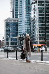 Winter city wanderlust: female tourist walking historic Warsaw old town, pastel facades and holiday lights, cozy coat, scarf and beanie. Urban sightseeing, slow travel, sustainable Europe escape eco.