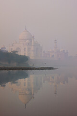Obraz premium View of Taj Mahal at sunrise reflected in Yamuna river with fog, Agra, Uttar Pradesh, India
