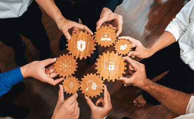 A diverse team collaborates with wooden gears showcasing security icons, symbolizing innovation and...