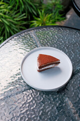 Indulge in a delicious chocolate cake slice presented elegantly on a modern white plate outdoors