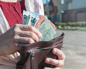 Leather wallet and euro banknotes in a woman's hands, selective focus.