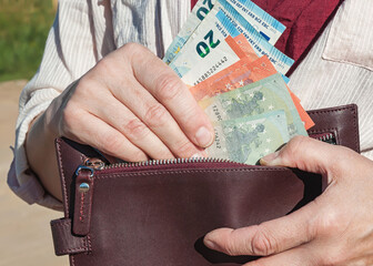 Leather wallet and euro banknotes in a woman's hands, selective focus.