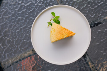 Enjoy a delicious slice of sponge cake with fresh mint garnish on a bright white plate for dessert