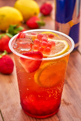 Strawberry Mojito Cocktail with Popping Pearls, Lime slice, and ice cube in plastic glass closeup side view of summer drink