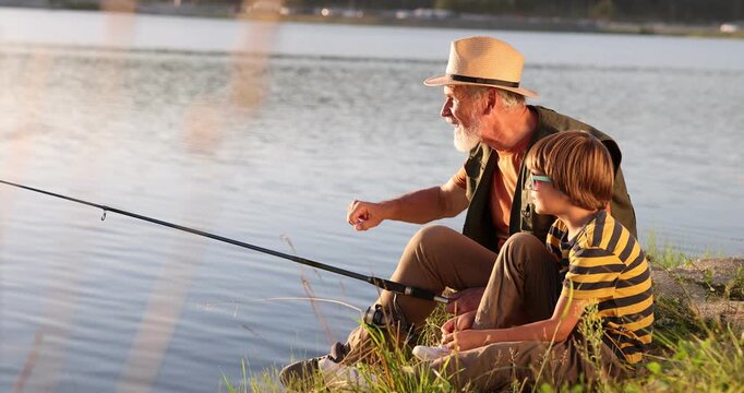 Emotional grandfather and his nephew fishing together near river outdoors