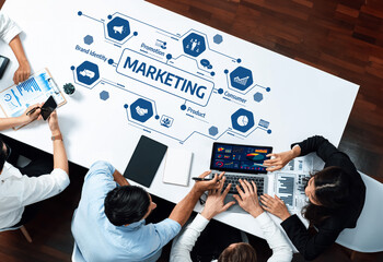 A diverse team of professionals collaborates on a marketing strategy, analyzing data and trends on laptops and charts at a modern workspace, showcasing innovation and teamwork. Amity