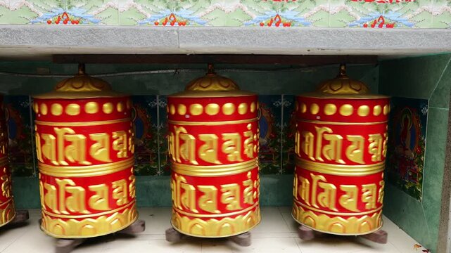 Rotating brass prayer wheels in Nepal monastery. Buddhist symbols, mantra engraving, spinning motion, cultural heritage, traditional ritual, spiritual architecture
