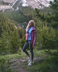 Naklejka premium Blonde Athletic Woman Admiring Mountain Views on Autumn Evening Hike in Forest Path