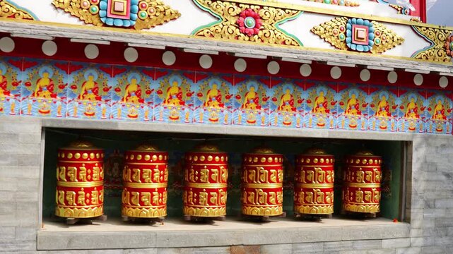 Rotating brass prayer wheels in Nepal monastery. Buddhist symbols, mantra engraving, spinning motion, cultural heritage, traditional ritual, spiritual architecture