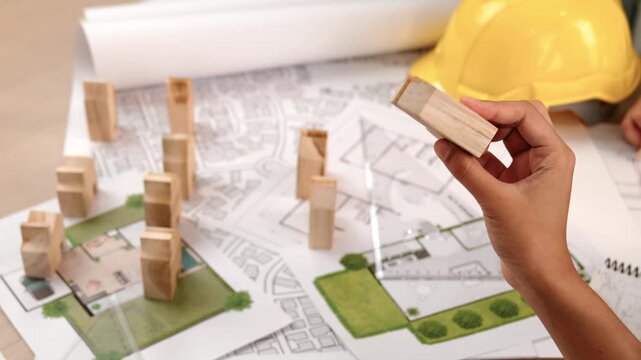 Architect and engineer consider or discuss about building construction using blueprint on table with architectural document, measurement tool and wooden block scatter around at office. Delineation.