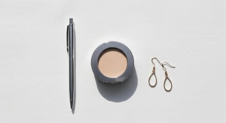 Minimalist Arrangement: Silver Pen, Compact Powder, and Teardrop Earrings on White Fabric
