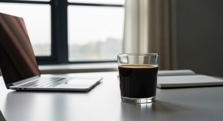 Morning workspace: Coffee, laptop, and notebook on a bright desk by the window