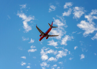 Plane flying overhead with scattered clouds in daytime