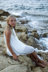 Little girl on the sea rock. Beautiful girl on the seashore.