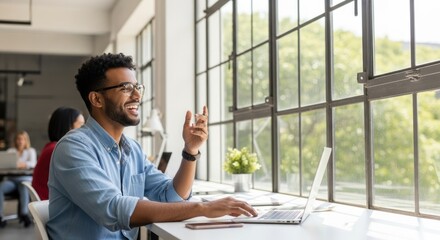 Smiling man working on laptop by window in bright office space