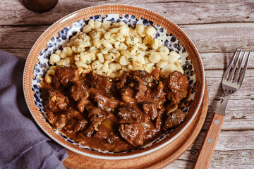 Delicious hungarian goulash with spaetzle on rustic wooden table