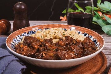 Delicious hungarian goulash with spaetzle and red wine being served on a table