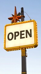 Retro open sign against a pale sky