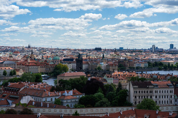 Obraz premium Cityscape view showcasing the skyline with historical buildings, bridge, and modern architecture under a blue sky filled with white clouds.