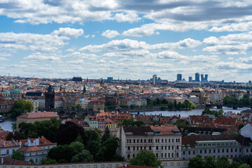 Cityscape view featuring historical architecture, a river, and modern skyscrapers under a bright, partly cloudy sky.