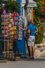 Naklejka premium Tourists choosing a souvenir on a colorful corner of Mogan
