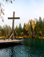 Wooden cross on a dock over a teal lake