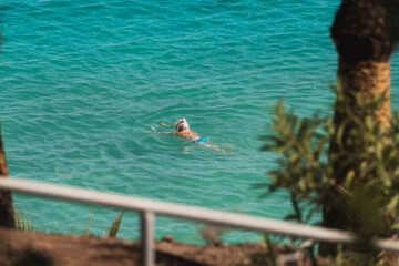 elderly woman swimming in turquoise waters of a beach
