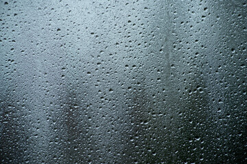 Moody window covered in water droplets on a rainy day. Perfect for background, weather themes, or emotional storytelling. Soft light and subtle reflections.